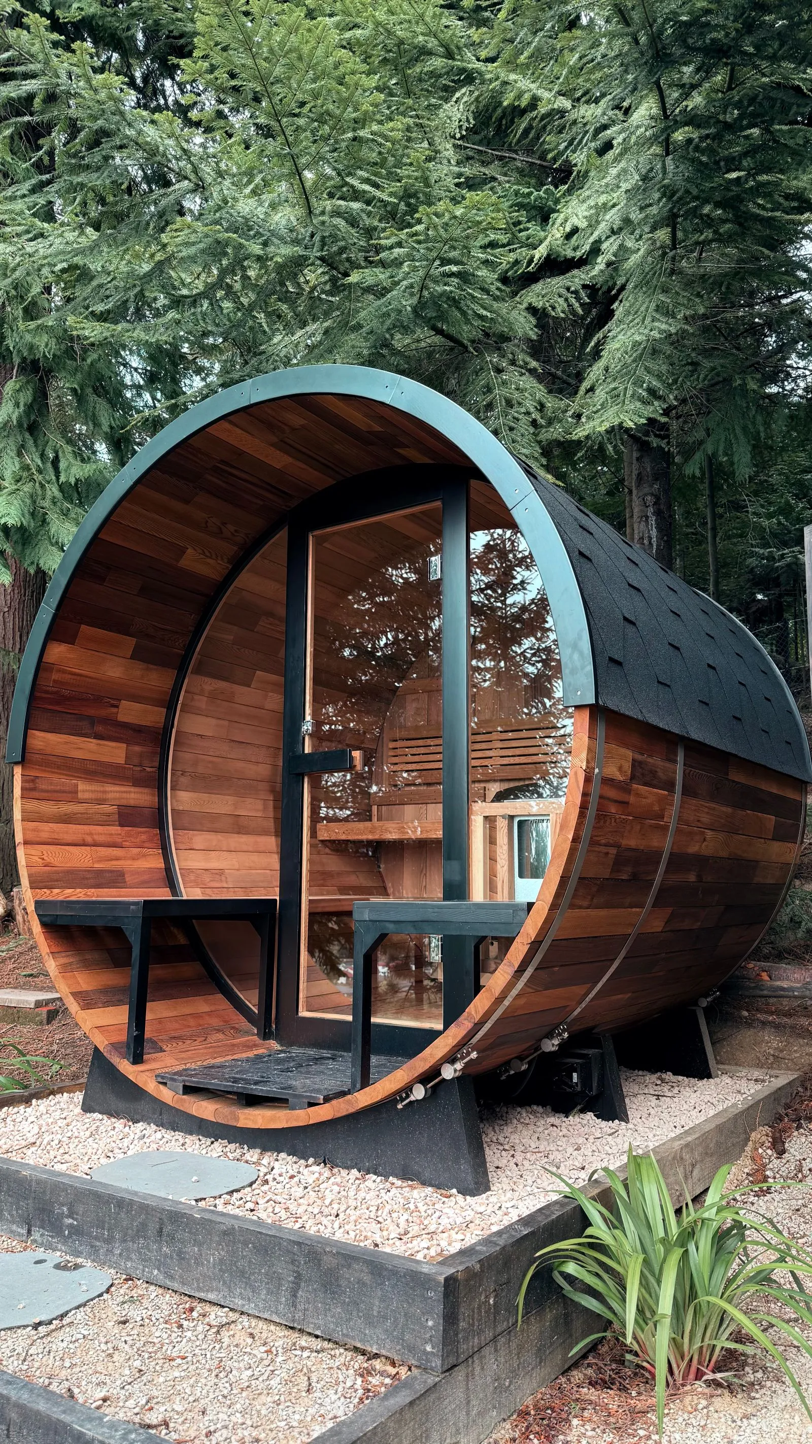 Cedar barrel sauna with a round window set among trees