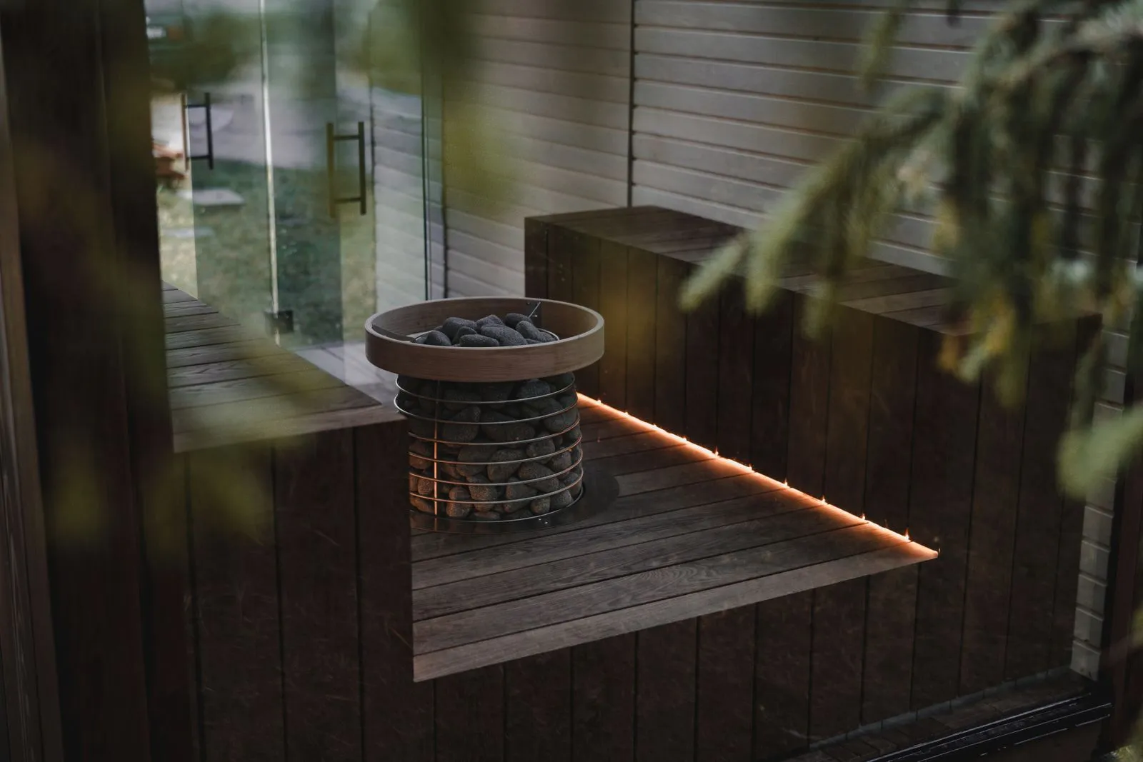 Modern electric sauna heater with stones inside a dark-wood Nordic sauna