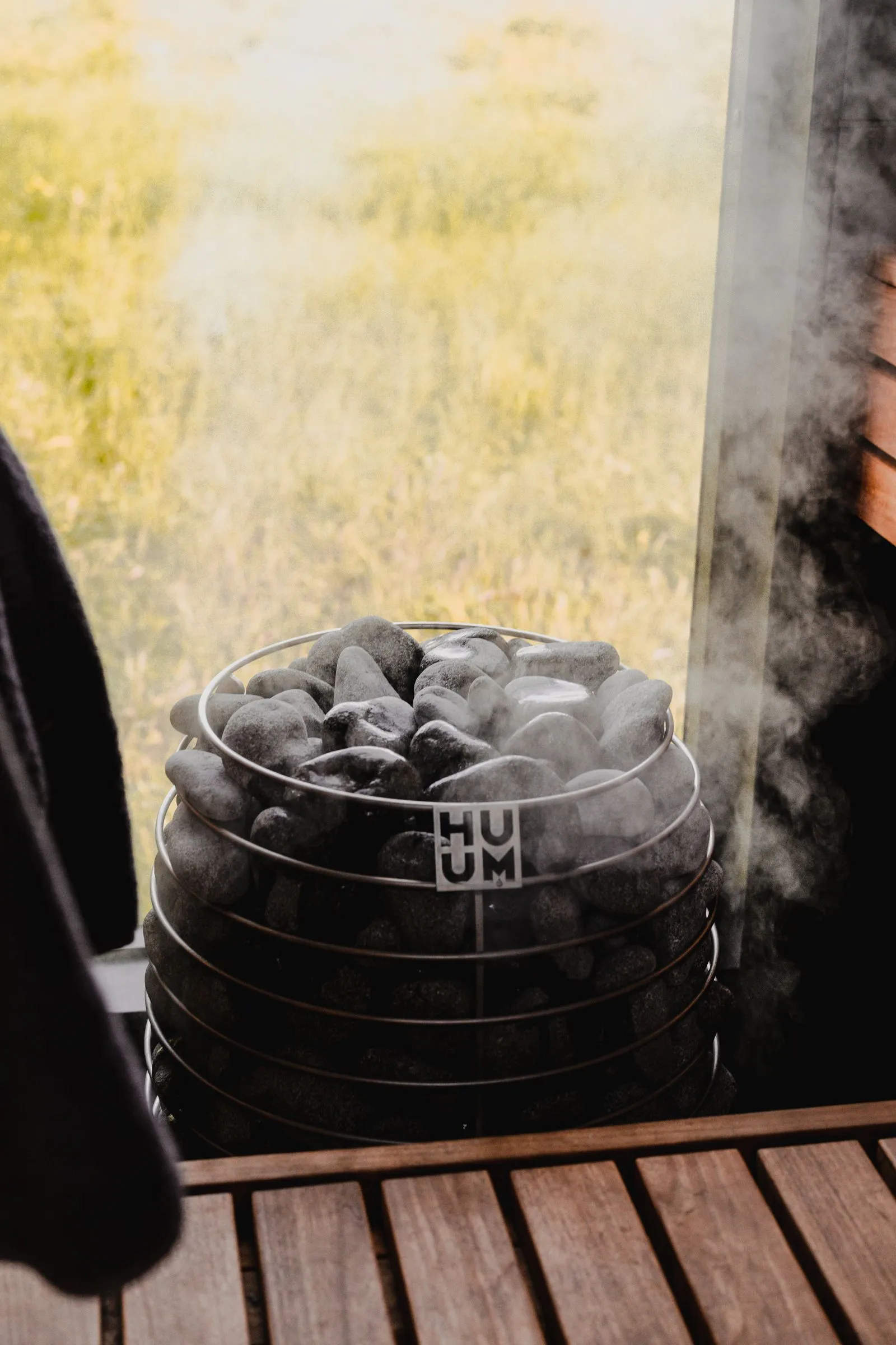Dark sauna stones stacked on a heater with steam rising