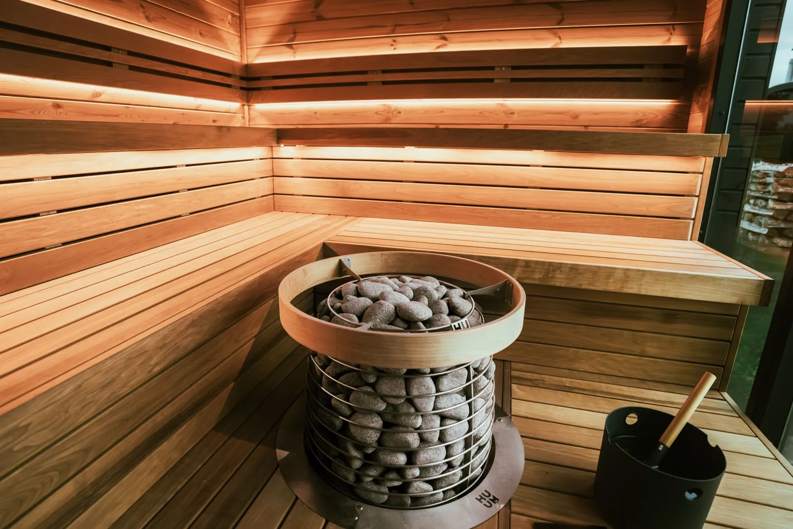 Wood-burning sauna stove with a black flue rising through the ceiling