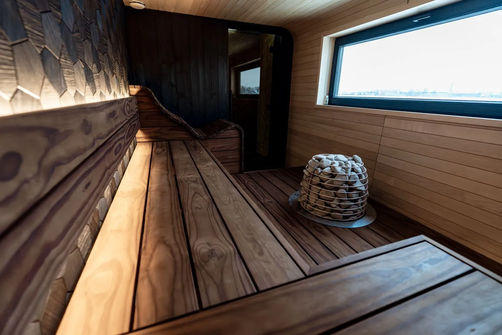 Wall-mounted sauna heater beside tiered wooden benches