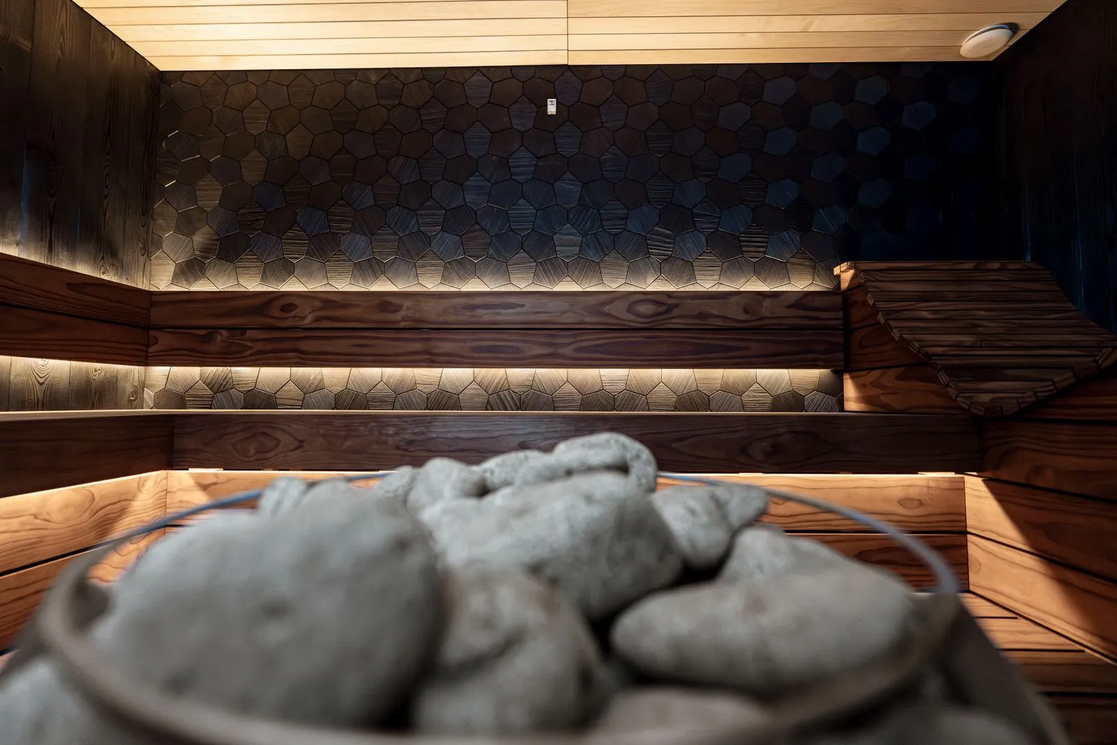 Sauna heater with stones being inspected in a wood-lined room