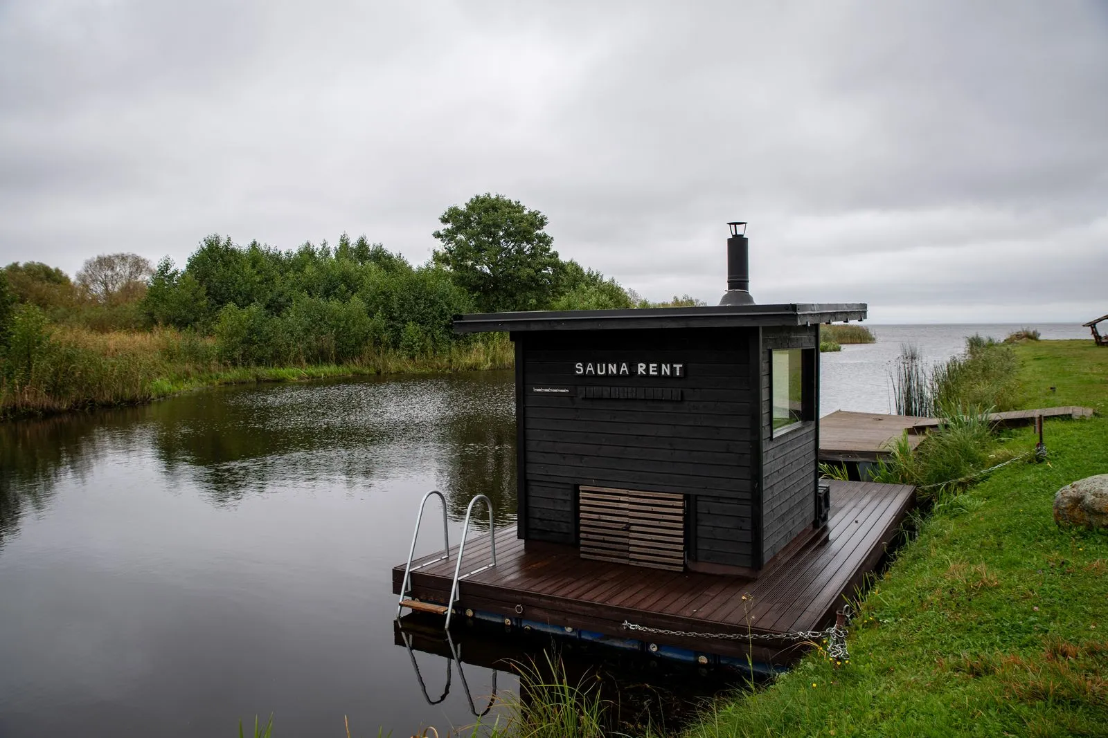 Compact outdoor sauna set beside water in a natural setting