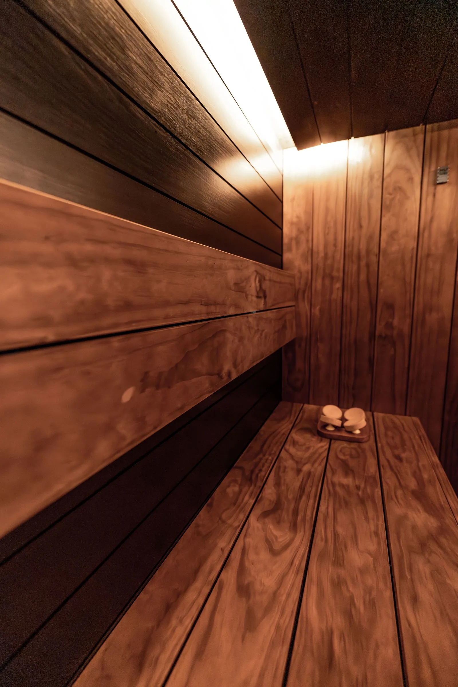 Electric sauna heater with stones in a dim wood-lined sauna