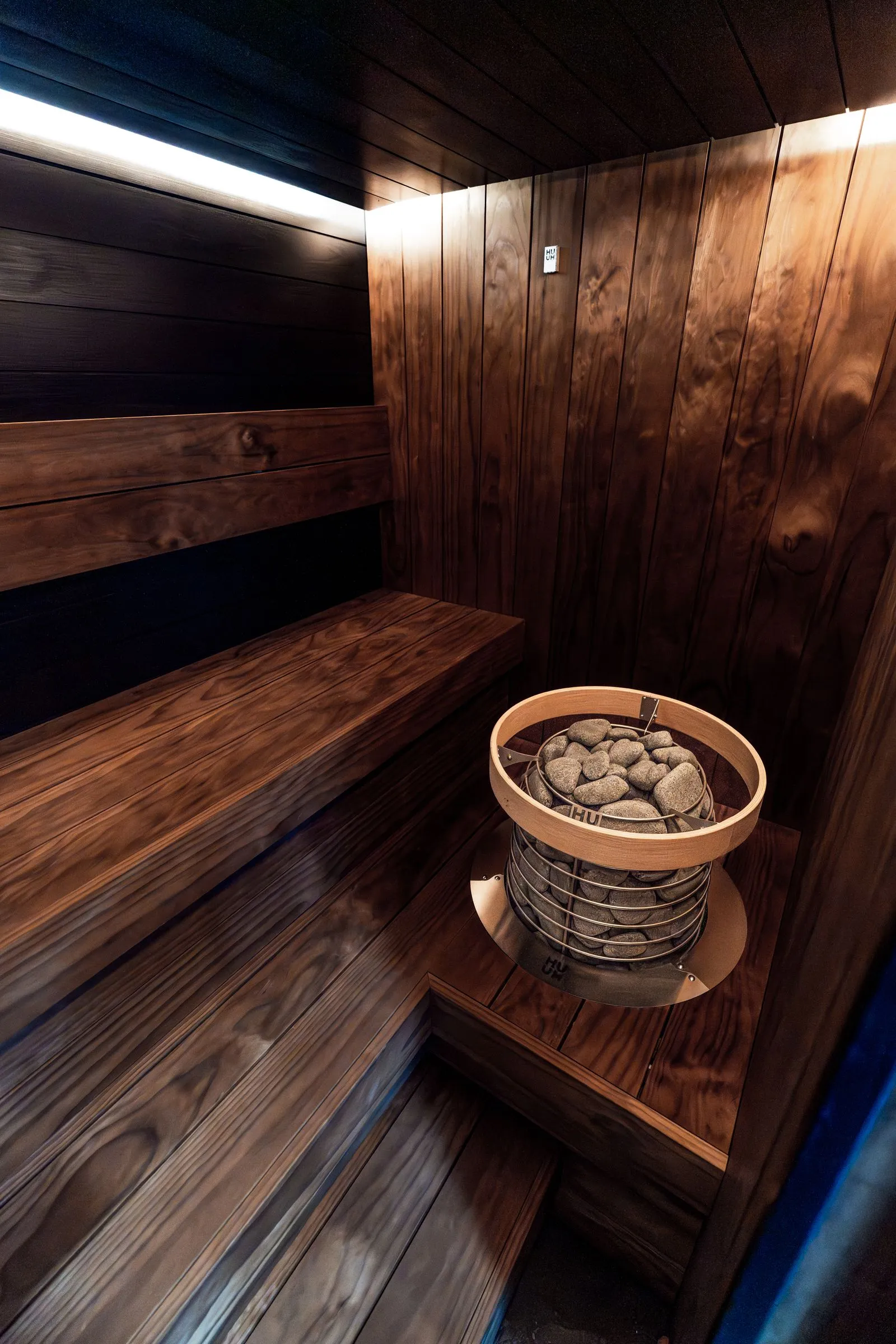 New electric sauna heater installed against a timber wall
