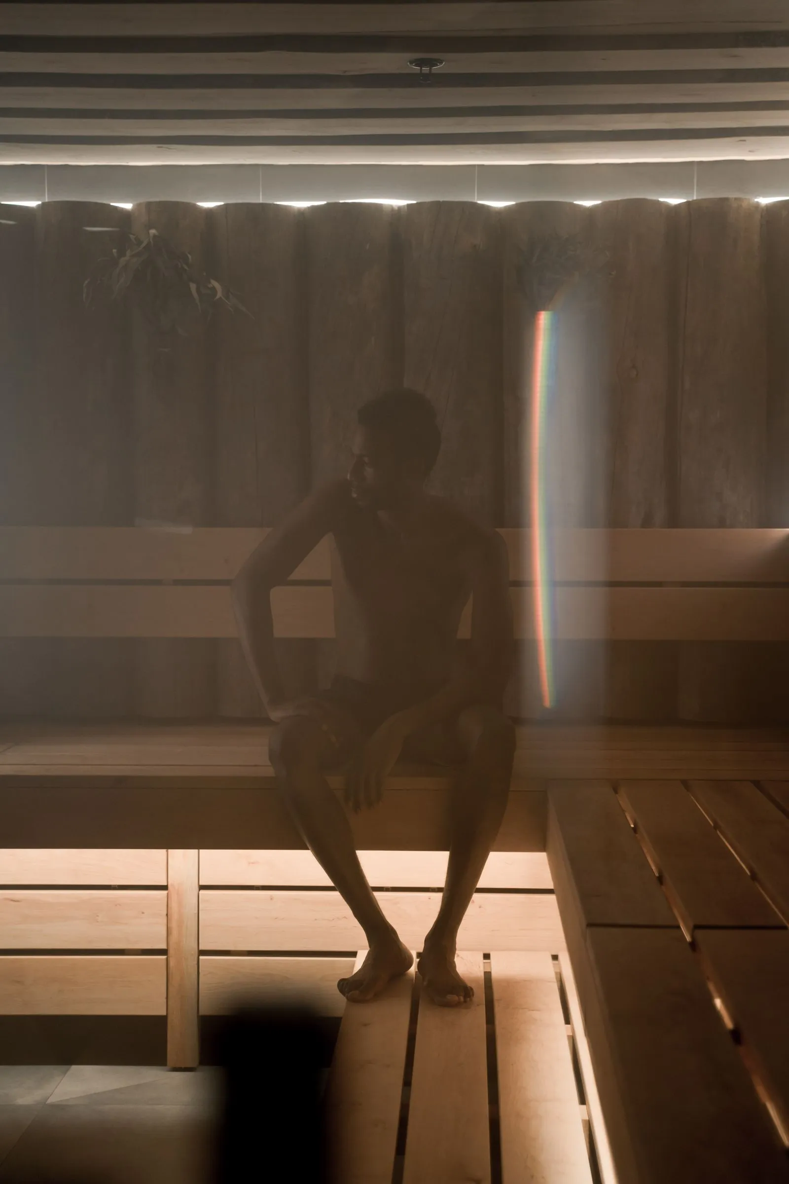 A person sitting on a wooden bench in a warm, softly lit sauna